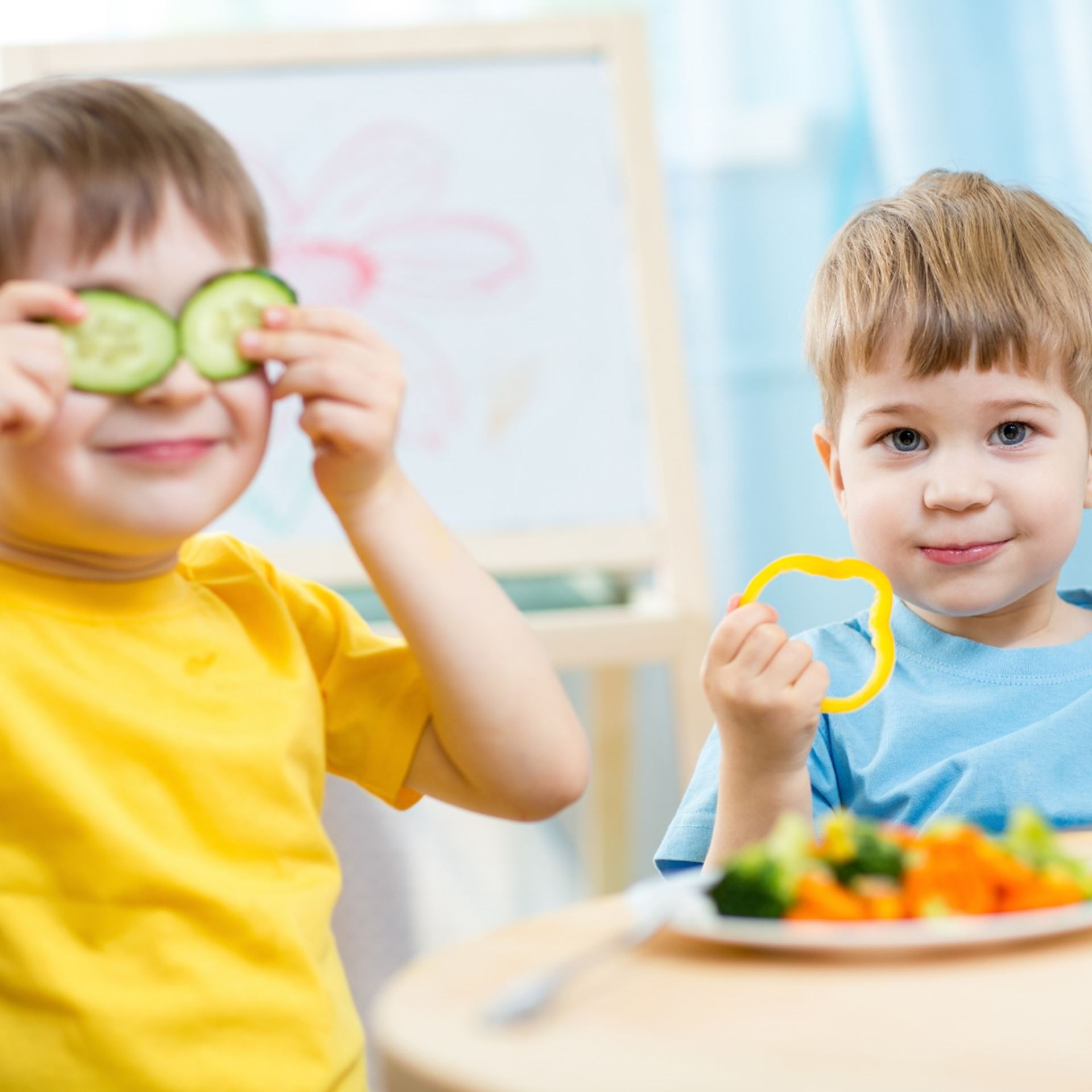 2 kids with with veggies in face